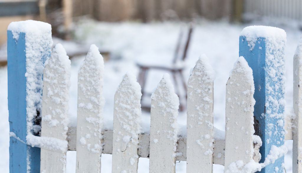 Snow Covered White And Blue Picket Fence With Falling Snow Flake