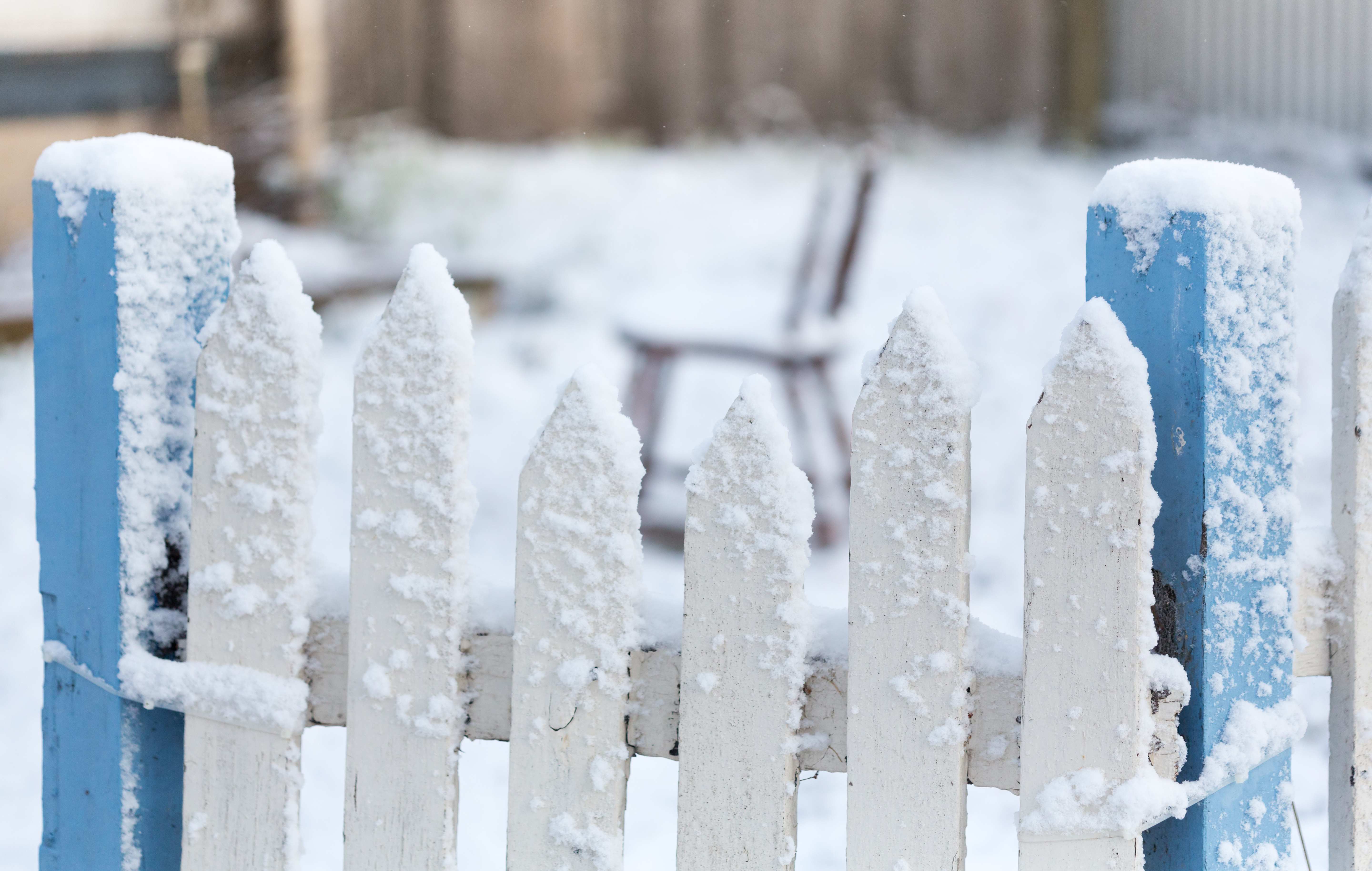 Snow Covered White And Blue Picket Fence With Falling Snow Flake